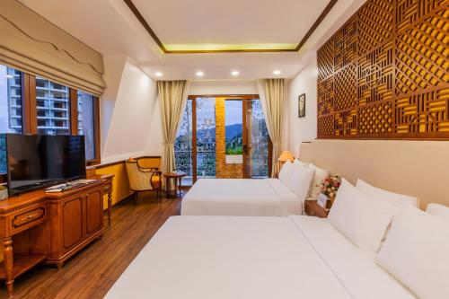 芽庄Boutik Cham NhaTrang Hotel的酒店客房设有两张床和一台平面电视。
