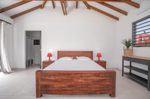 勒沃克兰Bungalow Pom 1, piscine, à 5 min des plages的一间卧室设有一张大木床和两个床头柜。