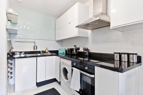 伦敦Modern 2 Bedroom Apartment in Hoxton的厨房配有白色橱柜、洗衣机和烘干机