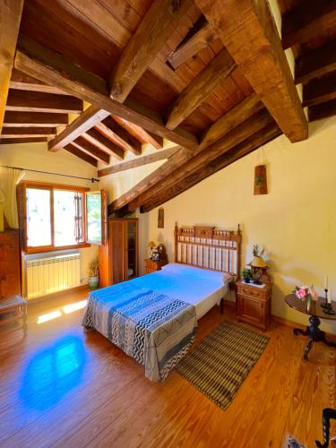 Montejo de la Vega de la SerrezuelaHOTEL RURAL LA HUERTA的一间带一张大床的卧室,位于一个拥有木制天花板的房间