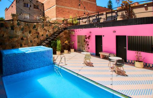 麦德林HOTEL BRANA的一座带椅子的游泳池以及一座粉红色的建筑