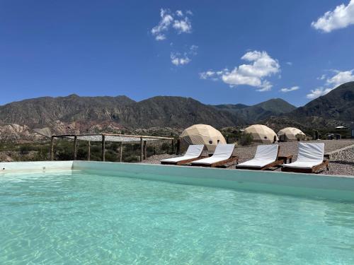 波特雷里约斯Denmoza Eco Lodge的一个带椅子的游泳池,背景是山脉