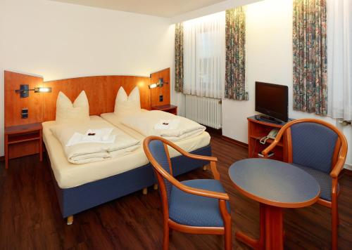 道恩施塔特道恩酒店的一间卧室配有一张床、一张桌子和一台电视