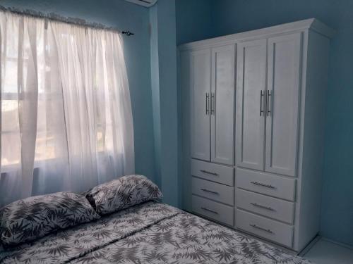 卡斯特里Avocado Suites的一间卧室配有一张床、一个梳妆台和一扇窗户。