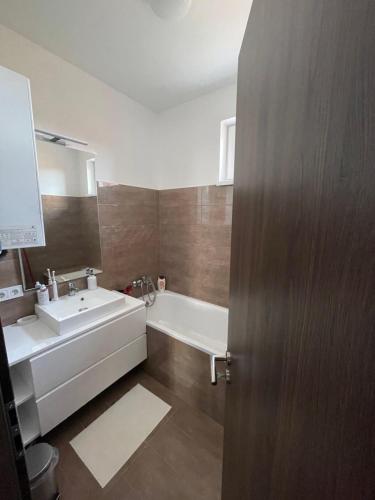 尼赖吉哈佐BRL Apartman的一间带水槽和浴缸的浴室以及一扇门