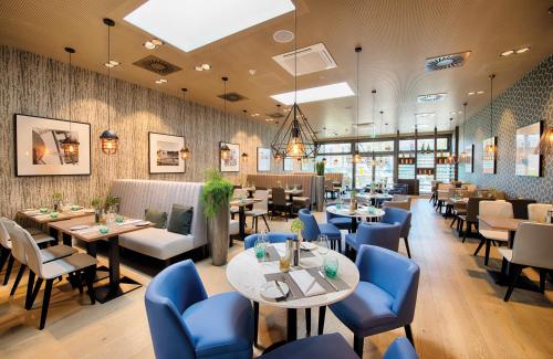 慕尼黑慕尼黑城市东部莱昂纳多酒店的一间配备有桌子和蓝色椅子的用餐室