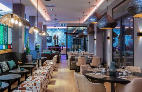 毕尔巴鄂NYX Hotel Bilbao by Leonardo Hotels的餐厅设有桌椅和吊灯。