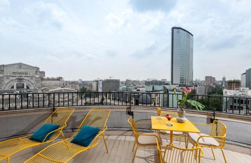 米兰NYX Hotel Milan by Leonardo Hotels的美景阳台的黄色桌椅