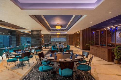 加济阿巴德Radisson Blu Kaushambi Delhi NCR的一间在房间内配有桌椅的餐厅