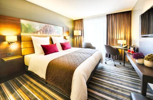 乌尔姆乌尔姆莱昂纳多皇家酒店的酒店客房配有一张带红色枕头的大床