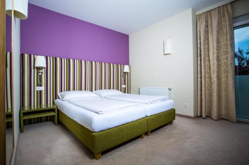 格拉茨巴宛伍特宾馆的卧室内的一张床位,带紫色墙壁