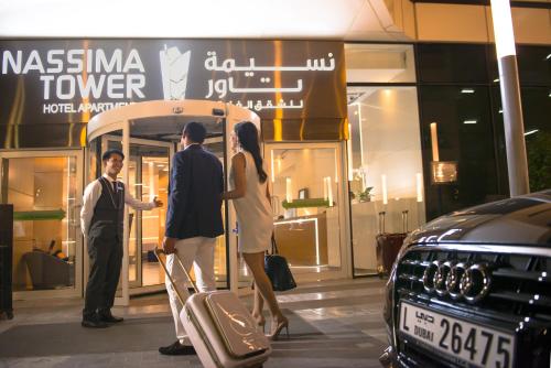 迪拜Nassima Tower Hotel Apartments的站在商店前的三人小组