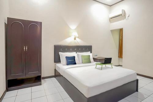 沙马林达Urbanview Hotel Gading Kencana Samarinda by RedDoorz的一间卧室配有一张大床和一个橱柜