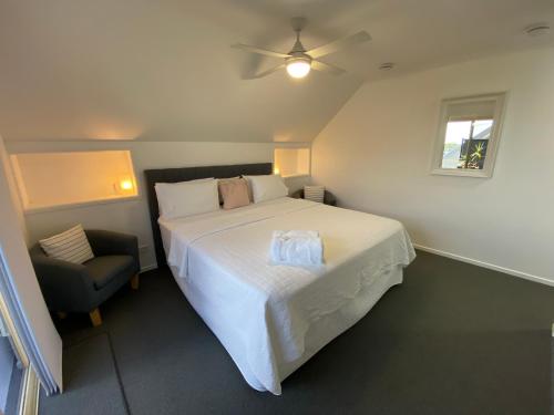 彩虹海滩Rainbow Beach Dream Studio Motel Style Apartment的卧室配有一张白色大床和一把椅子