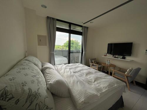 金湖镇金門民宿 x 花藝雅築 The Flower Hut的一间卧室设有一张床、一台电视和一个窗口。