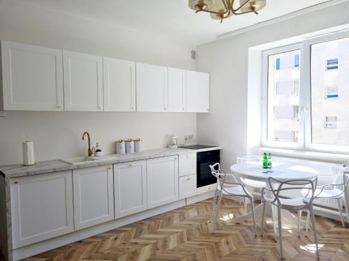 格丁尼亚Sun and holidays apartament Abrahama的厨房配有白色橱柜、桌子和窗户。