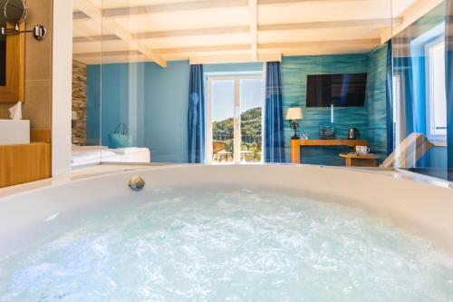 卡迪马里奥Kurhaus Cademario Hotel & DOT Spa - Ticino Hotels Group的蓝色墙壁的客房内设有一个按摩浴缸