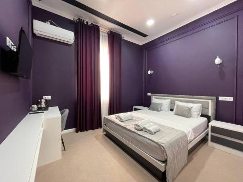 费尔干纳Emin hotel的一间卧室设有紫色的墙壁、一张床和一张书桌