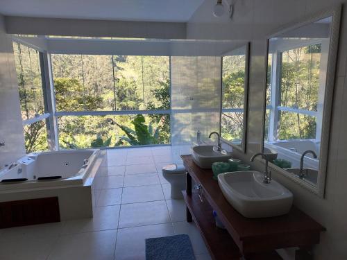 新弗里堡Lumiar Eco Lodge - Chalé Telhado Verde的一间带两个盥洗盆的浴室和一个大窗户