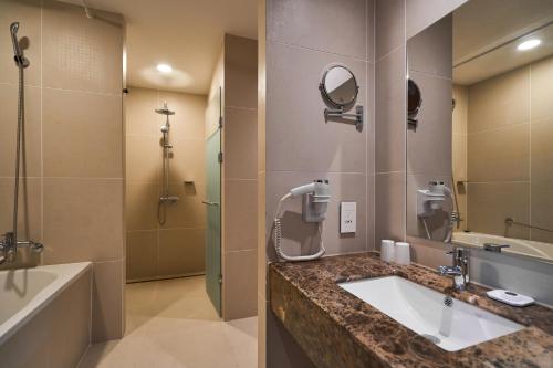 安山市安山广场酒店的浴室配有水槽、淋浴和浴缸。
