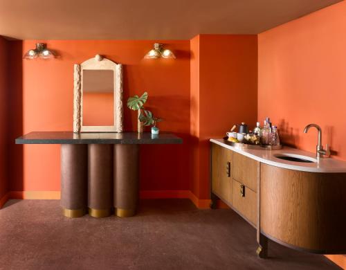 迈阿密Mayfair House Hotel & Garden的浴室设有橙色墙壁、水槽和镜子