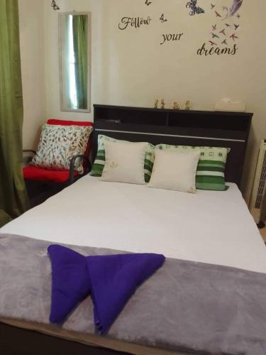 CaintaBudget Friendly Staycation in Valley Golf的一间卧室配有一张大床,上面有紫色的领带