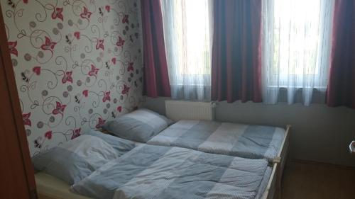比克Réka Apartman的卧室内的一张小床,配有红色窗帘