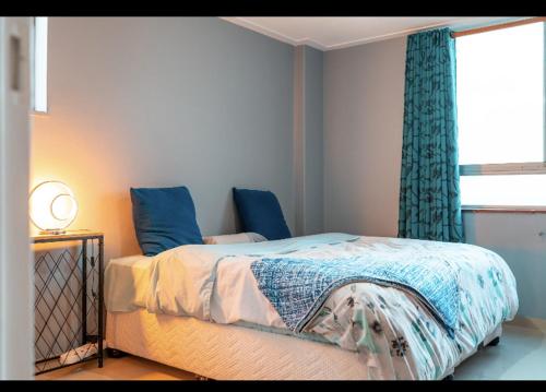 KingsboroughMai Paradise的一间卧室配有一张带蓝色窗帘的床和一扇窗户