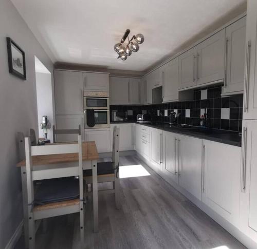 瑟索B'Dazzled Flat, Castletown的厨房配有白色橱柜、桌子和用餐室。