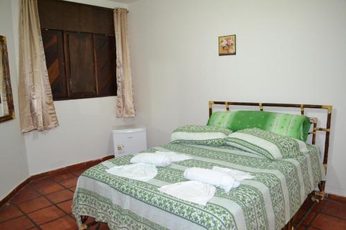 吉尼帕布Pousada Rosa dos Ventos的一间卧室配有绿床和毛巾