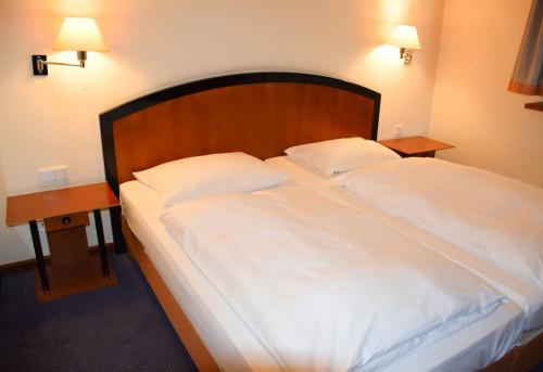 拉德博伊尔德累斯顿拉德博伊尔城市酒店的一张带白色床单的大床和2个床头柜