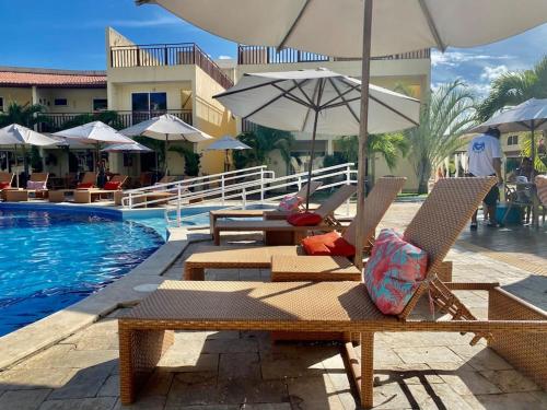 皮帕Flat Solar Água 127 - Family & Friends的游泳池旁的游泳池配有椅子和遮阳伞