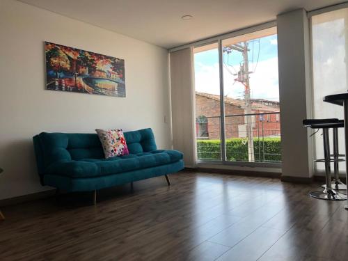 奇亚Espectacular apartamento con estacionamiento gratuito Chía N 2的客厅设有蓝色的沙发和大窗户