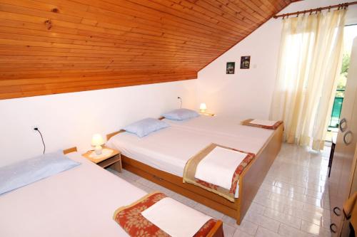 弗班吉Apartments by the sea Basina, Hvar - 542的一间卧室设有两张床和木制天花板