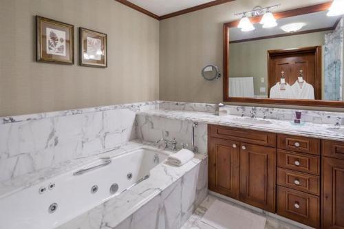 阿斯潘Aspen Ritz-carlton 3 Bedroom Ski In, Ski Out Residence Includes Slopeside Heated Pools And Hot Tubs的一间带浴缸和大镜子的浴室