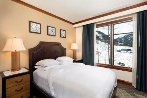 阿斯潘Aspen Ritz-carlton 3 Bedroom Ski In, Ski Out Residence Includes Slopeside Heated Pools And Hot Tubs的卧室设有一张白色大床和一扇窗户。