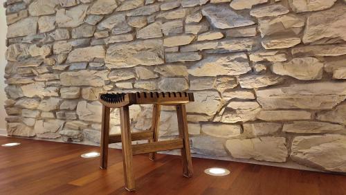 杜伊诺dalTURRI - Casa vacanze al mare - Relax e PRIVATE WELLNESS con sauna的石墙前的木凳