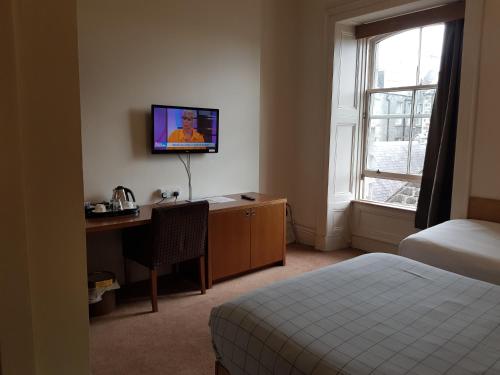 阿伯丁Aberdeen House的酒店客房配有书桌、床和电视。