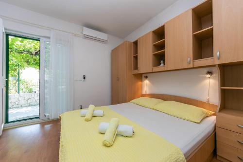 布雷拉Apartments with a parking space Brela, Makarska - 6907的一间卧室设有两张带黄床单的床和窗户。