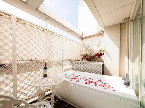 神户V酒店（仅限成人）的浴缸、桌子和一瓶葡萄酒