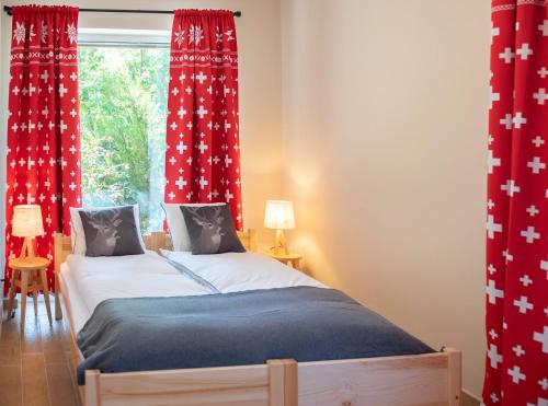 施瓦尔茨湖Chalet Alte Post的一间卧室配有两张带红色窗帘的床和窗户。