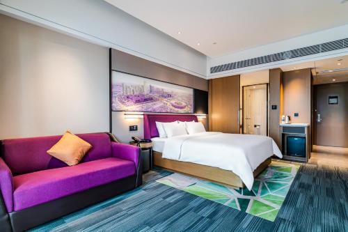 佛山敏卓酒店Mentor Hotel的酒店客房设有一张床和一张紫色沙发