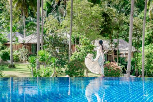 奥南海滩Ban Sainai Resort- SHA Extra Plus Aonang's Green Resort的身着连衣裙的女人站在游泳池旁