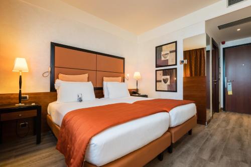 卡萨诺韦米兰马尔彭萨机场皇冠假日酒店的一间卧室配有一张带橙色毯子的大床