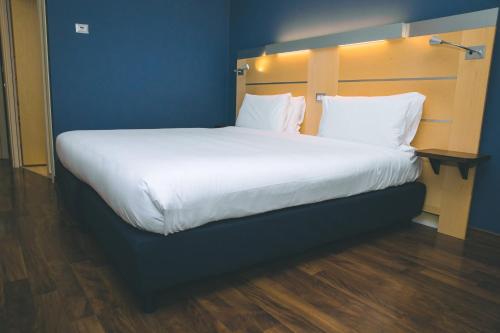 卡萨诺韦米兰马尔彭萨快捷假日酒店的一张配有白色床单和枕头的大床