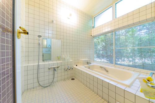 伊东コテージいっぺき湖的带浴缸的浴室和窗户。