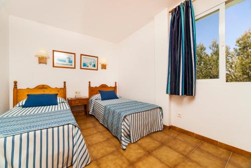 卡拉维尼耶斯Globales Apartamentos Cala Viñas ONLY ADULTS 16的带2扇窗户的客房内的2张床