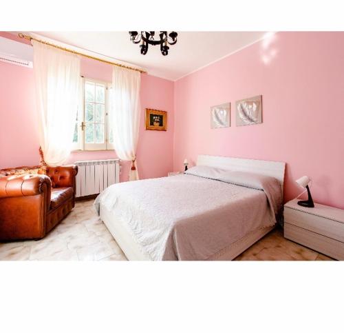 奥古斯塔Villa Angela的卧室设有粉红色的墙壁、一张床和椅子