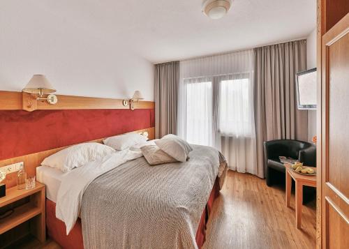克勒施特勒der klostertalerhof的酒店客房带一张大床和一把椅子