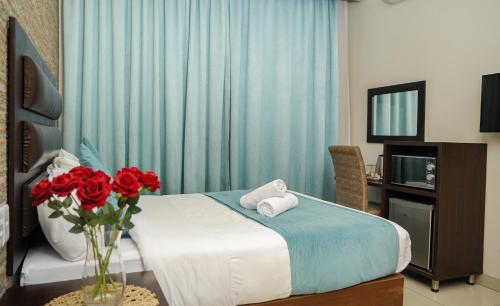 彼得马里茨堡Bayside Hotel Pietermaritzburg的一间卧室,配有一张带红玫瑰花瓶的床